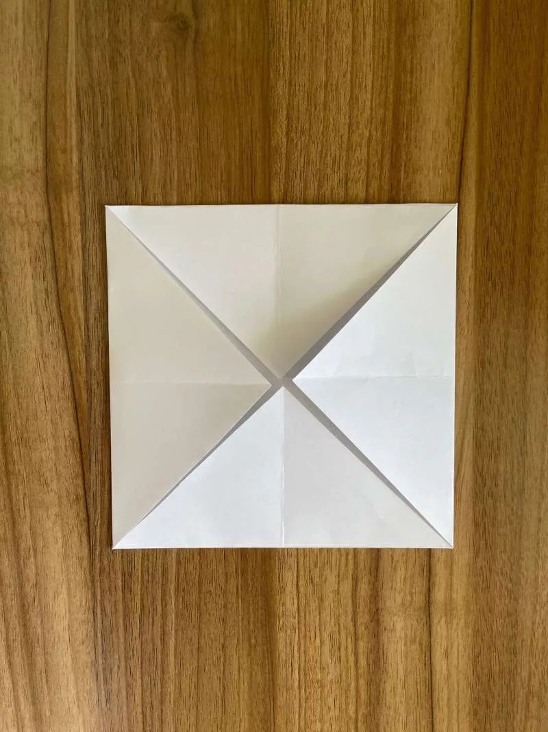 A piece of paper folded into 4 triangles that meet in the middle. A piece of paper folded into 4 triangles that meet in the middle.