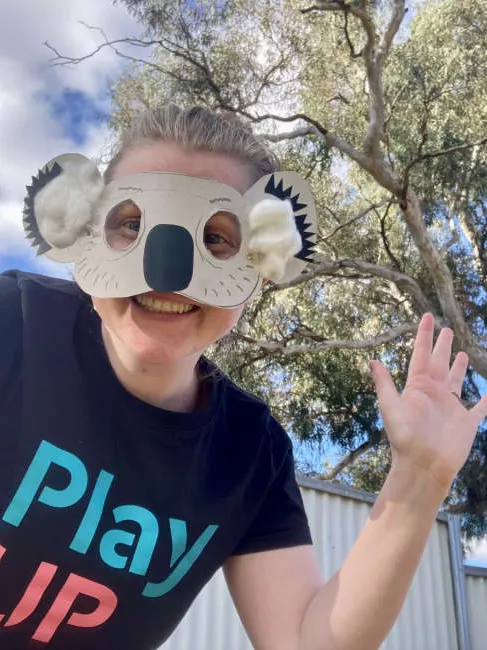 A PlayUp facilitator wears a koala mask outside. 