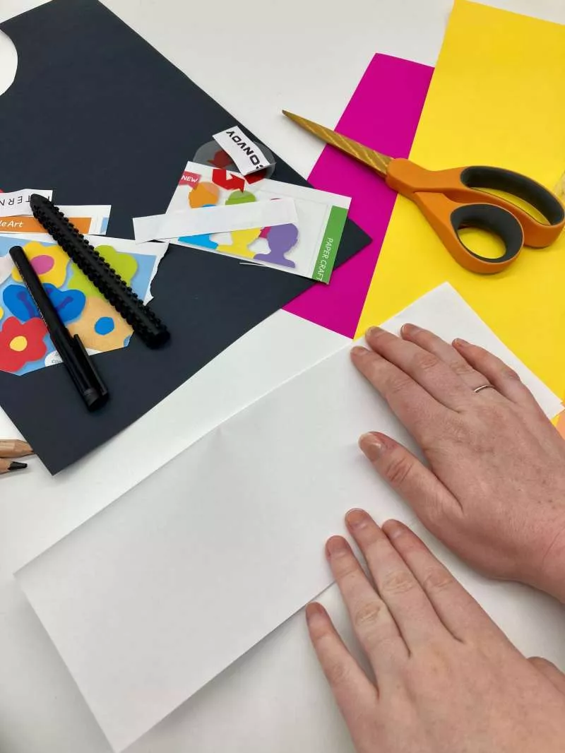 A close up of two hands folding a piece of A4 paper in half. A close up of two hands folding a piece of A4 paper in half.