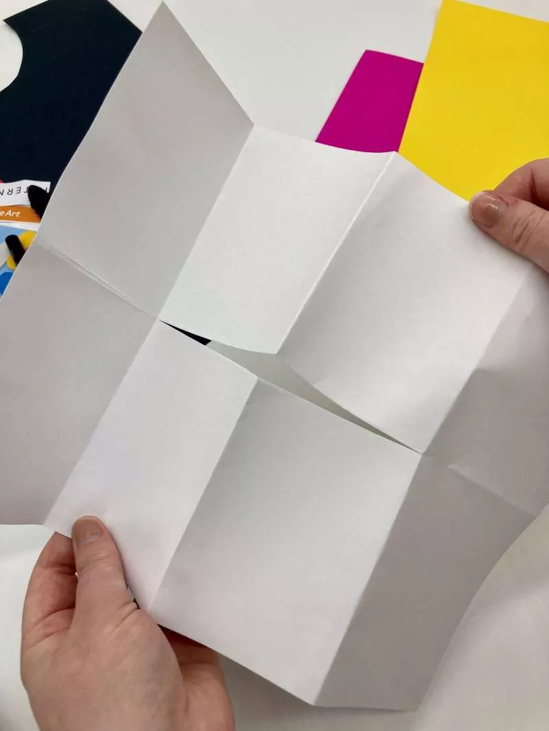 A piece of A4 paper with creases representing 8 sections and a cut in the centre of the paper. A piece of A4 paper with creases representing 8 sections and a cut in the centre of the paper.