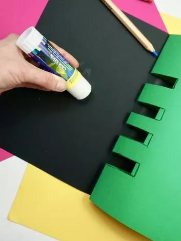A person is glueing a black piece of paper. A person is glueing a black piece of paper.