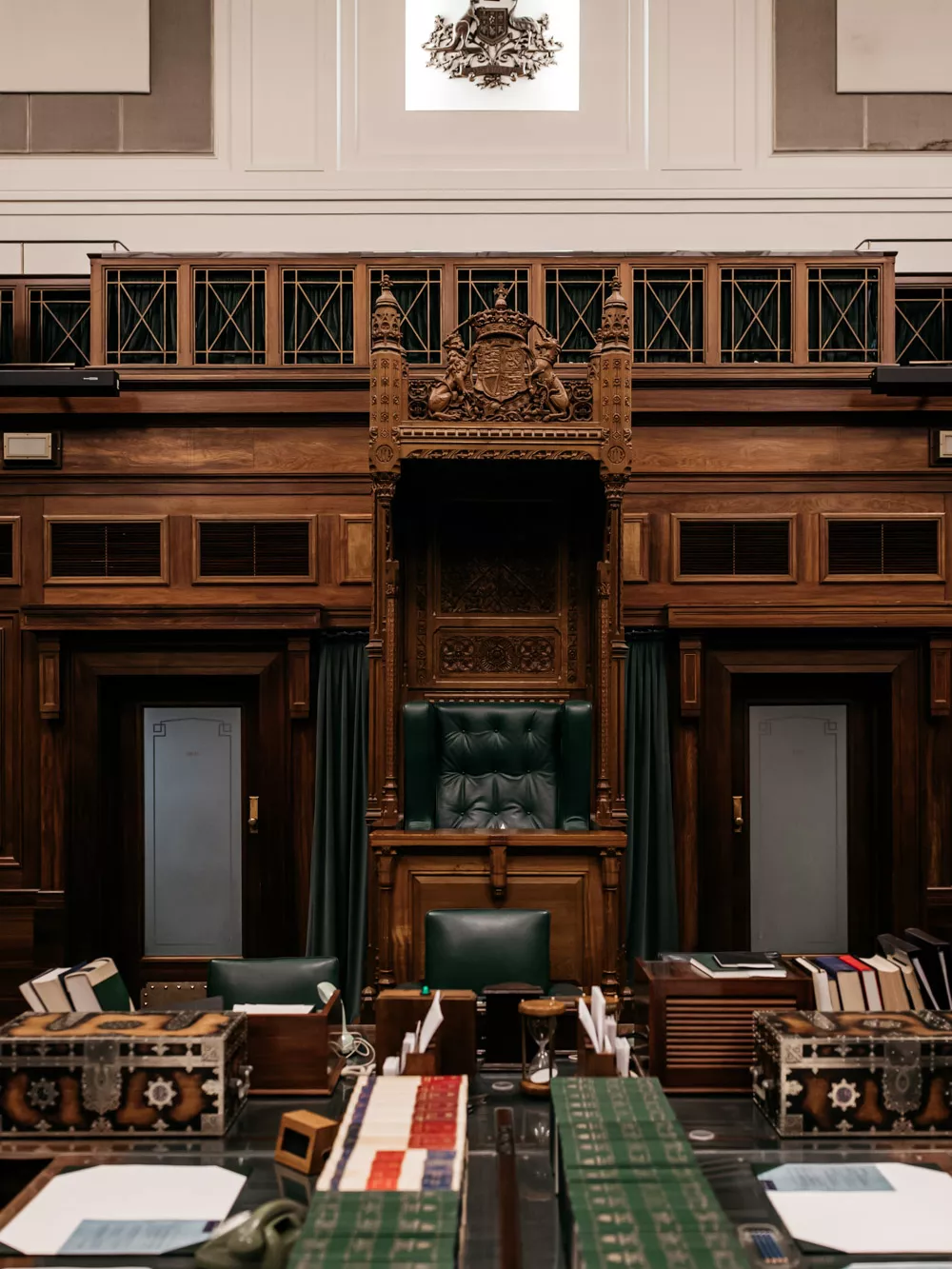 A close up detail shot of the table in the House of Representatives Chamber covered with leather bound books, a mace and 2 chests.