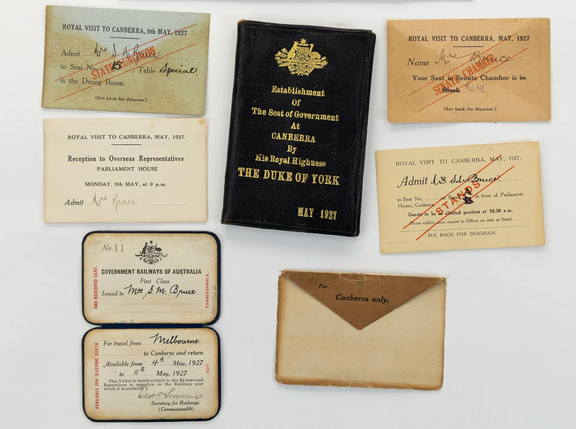 A black leather wallet with the Australian Coat of Arms and 'Establishment of the seat of Government at Canberra by His Royal Highness The Duke of York May 1927' embossed in gold, an envelope, first class railway ticket from Melbourne to Canberra for Mrs Bruce for travel from 4th May to 11th May 1927, rectangular tickets to the State Luncheon, Senate Chamber, Stands and Reception at Parliament House.