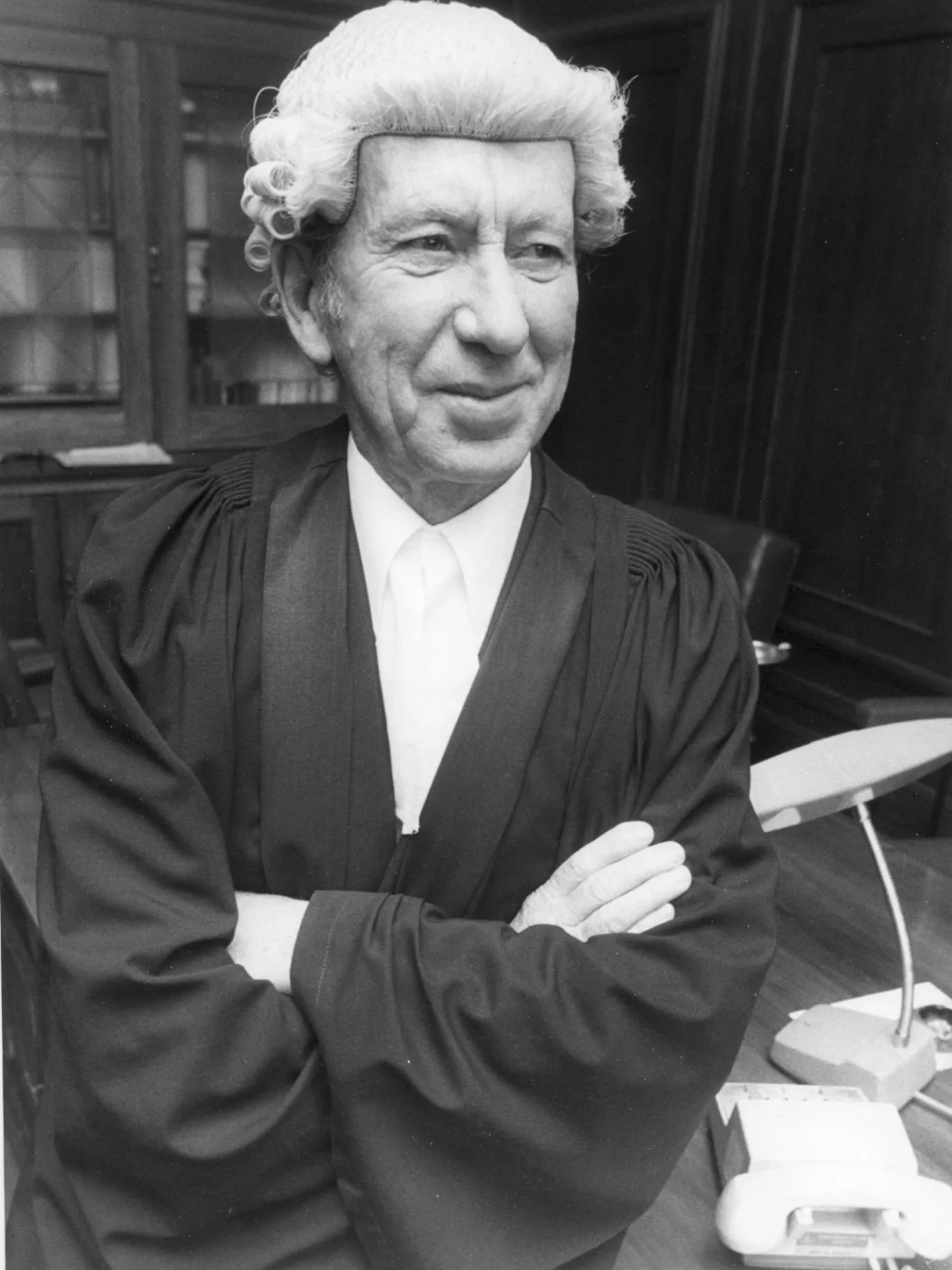 Clerk of the Senate James Odgers wearing a black gown and white wig sits on his desk at Old Parliament House around 1976.