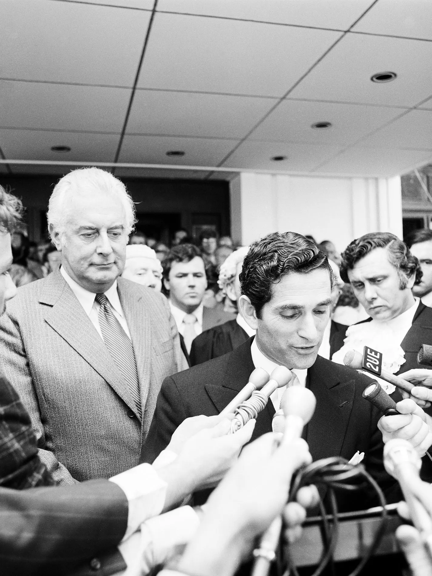 David Smith reads a proclamation on the steps of Parliament House watched by Gough Whitlam and crowds.