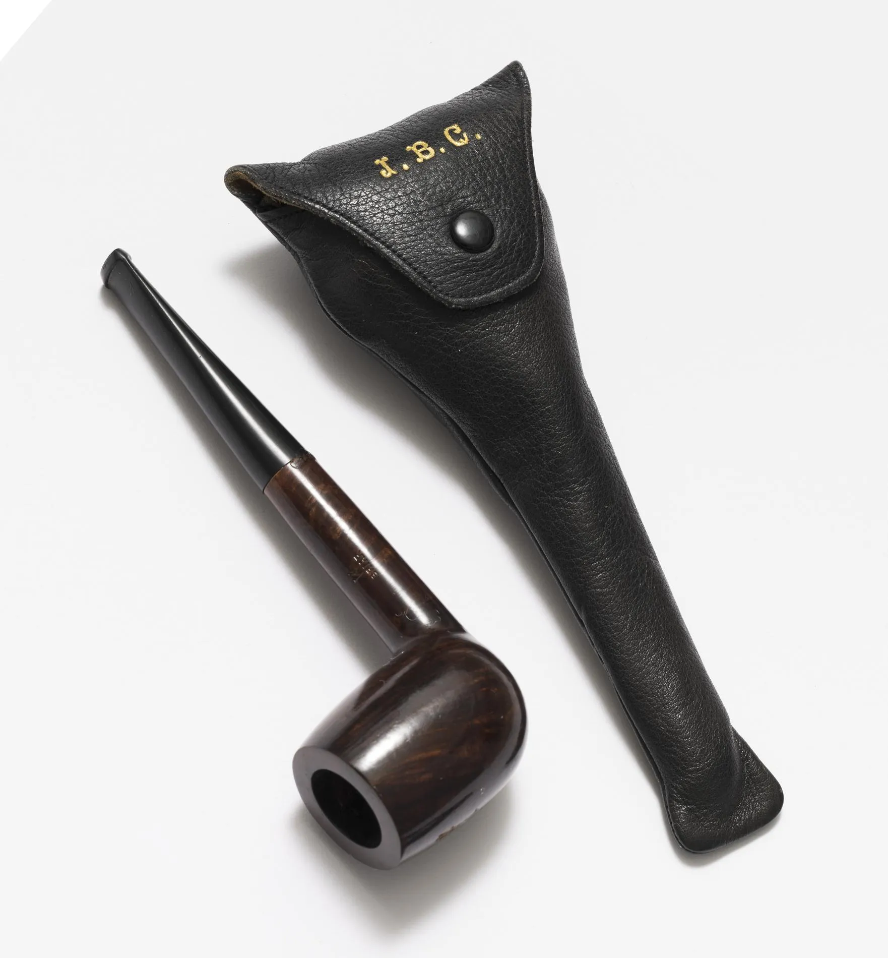 An old tobacco pipe that belonged to Ben Chifley next to its case. The case features golden lettering of the initials J. B. C.