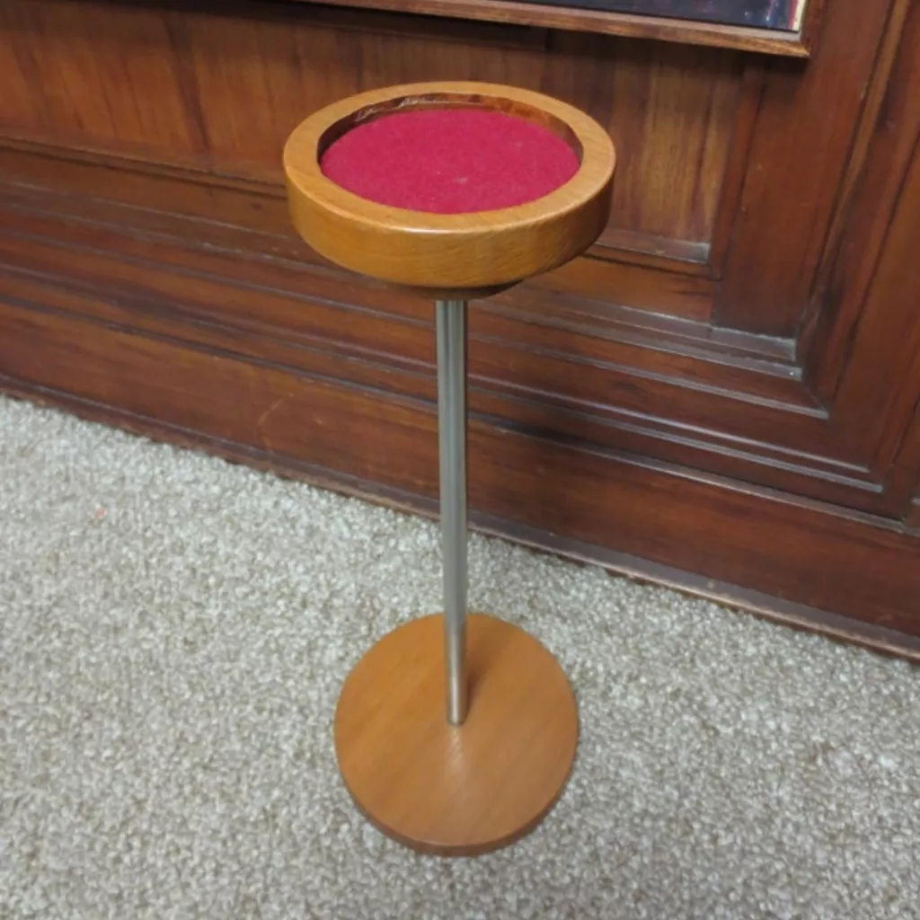 A round wooden stand with a metal pole with wooden base.