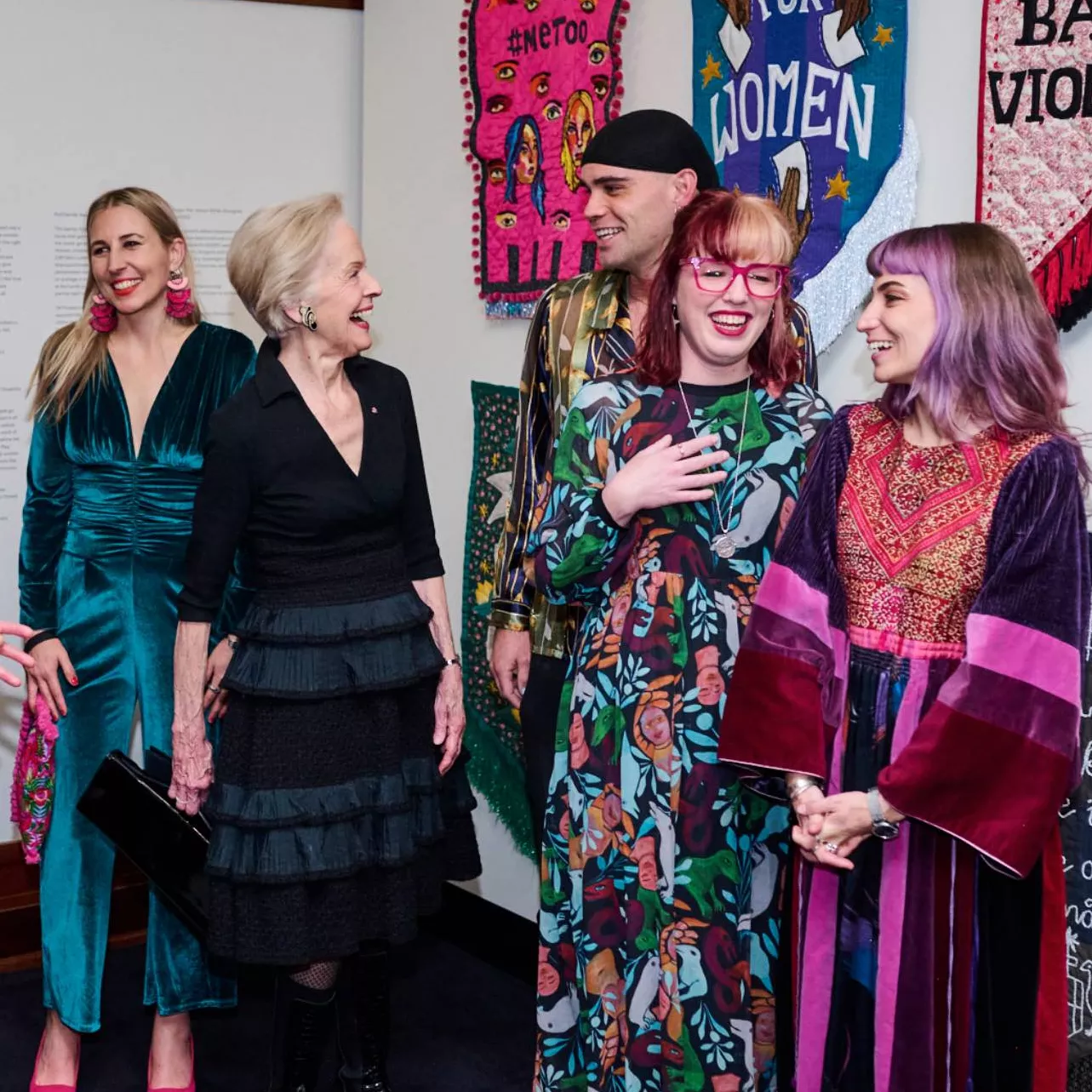 Quentin Bryce chats to artists in front of embroidered banners at the front of the Changemakers exhibition at MoAD.