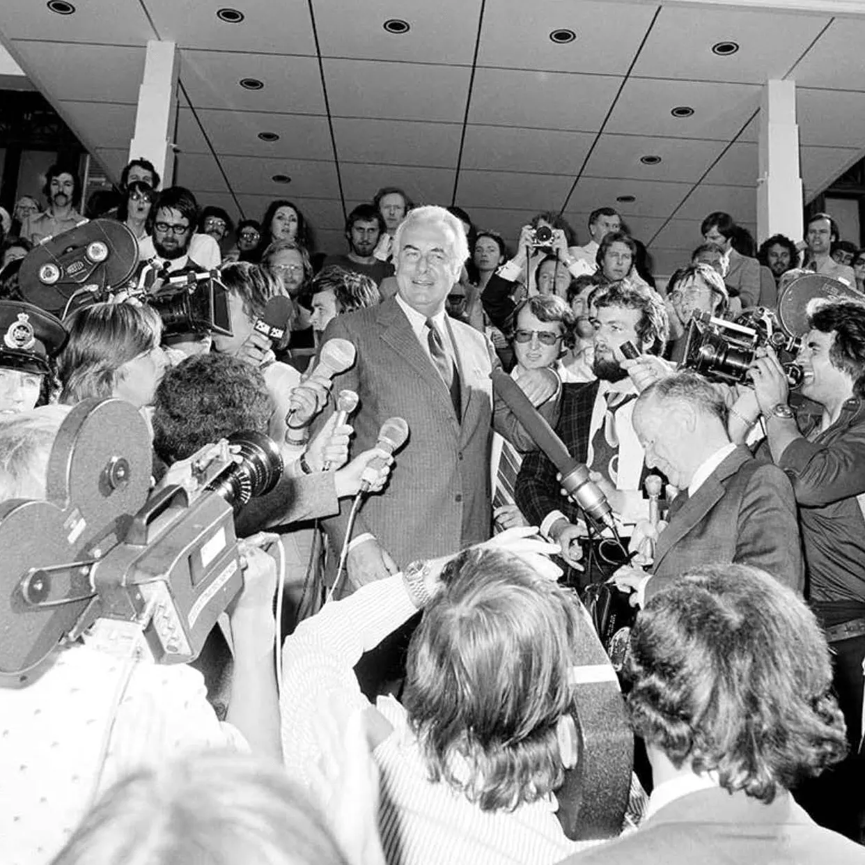 A man walking through a crowd of reporters down the Old Parliament House steps