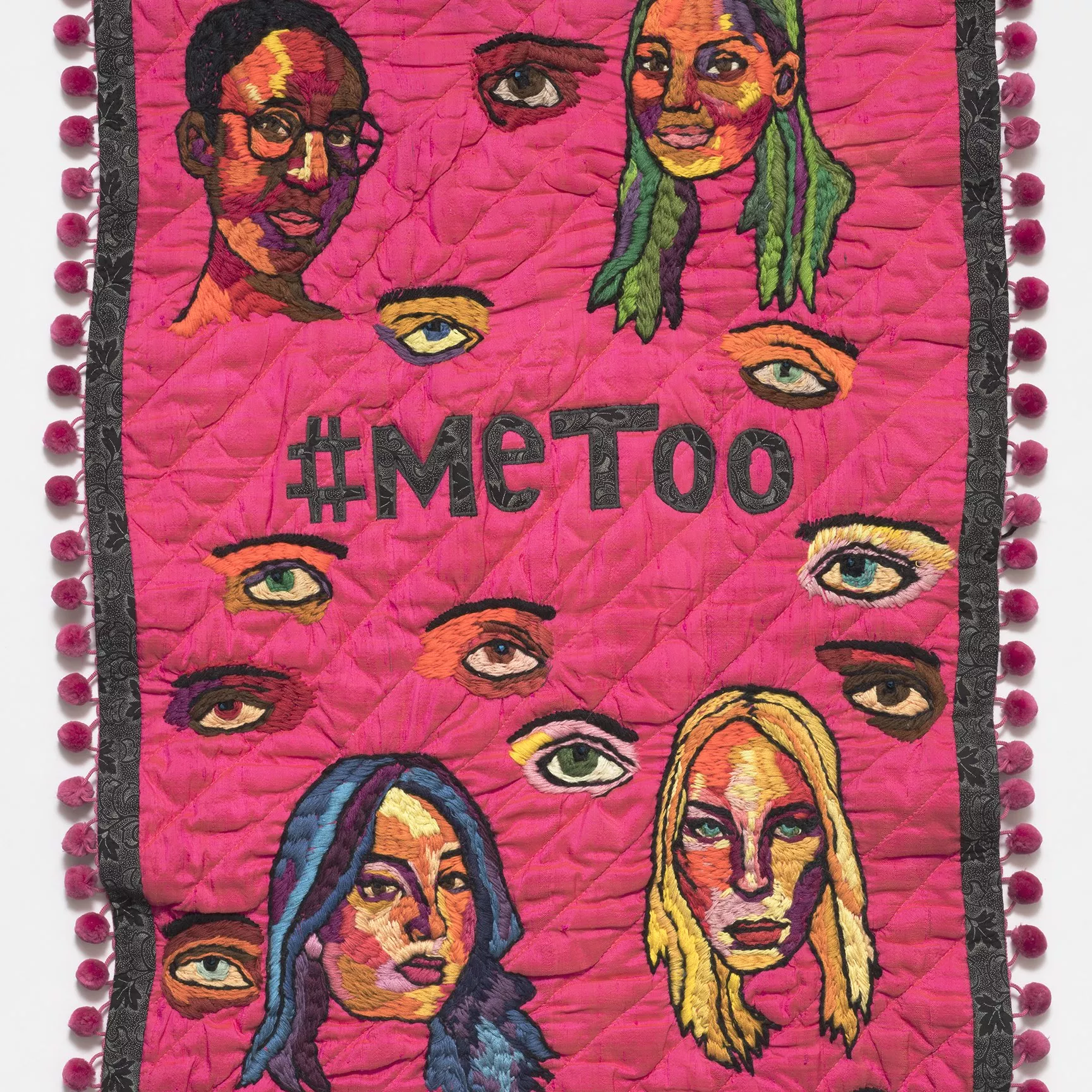 A pink embroidered banner with the words #metoo in the centre and images of women's face surrounding it. 