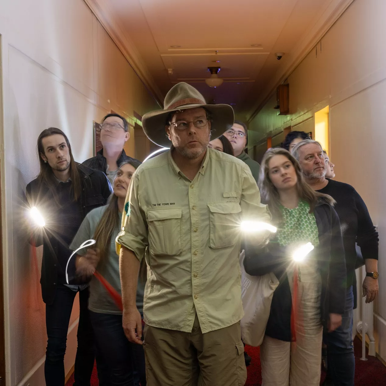 Tim the Yowie Man leading a group of people down a corridor in Old Parliament House.