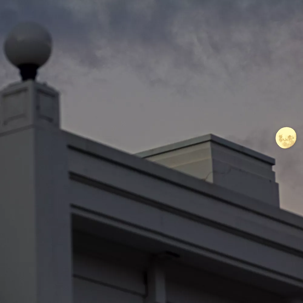 A section of the Old Parliament House building, with the moon in the night sky in the background.