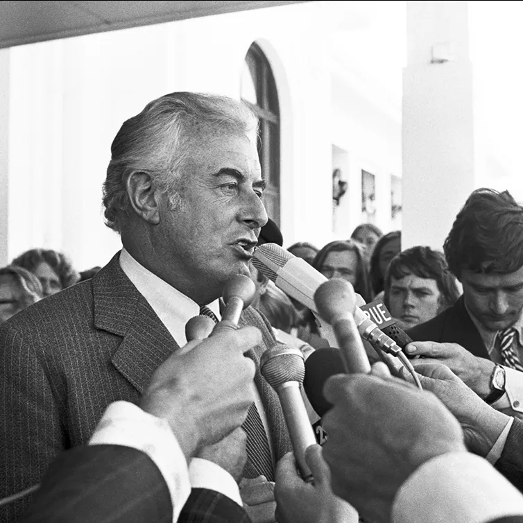 Gough Whitlam talks into multiple microphones on the steps of Old Parliament House.