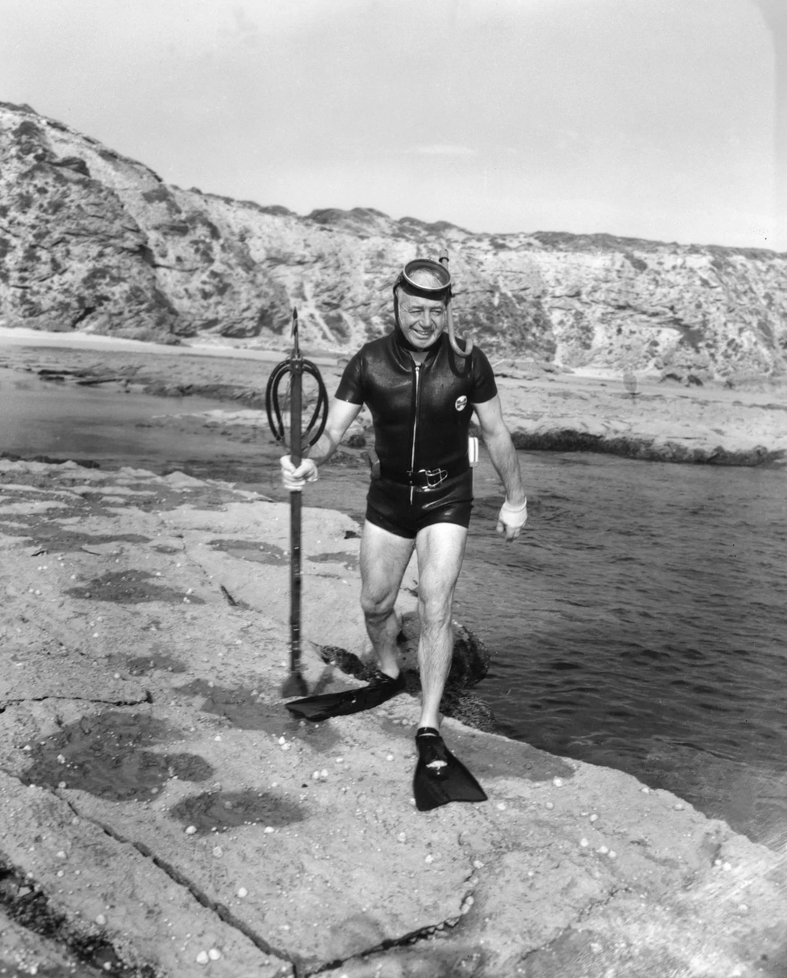 Prime Minister Harold Holt at Portsea, Victoria in 1966, where he later disappeared while swimming in heavy seas. Photograph Australian News and Information Bureau, NAA: A1200, L54379 Prime Minister Harold Holt wearing a wetsuit and flippers on the rocks at Portsea, Victoria.