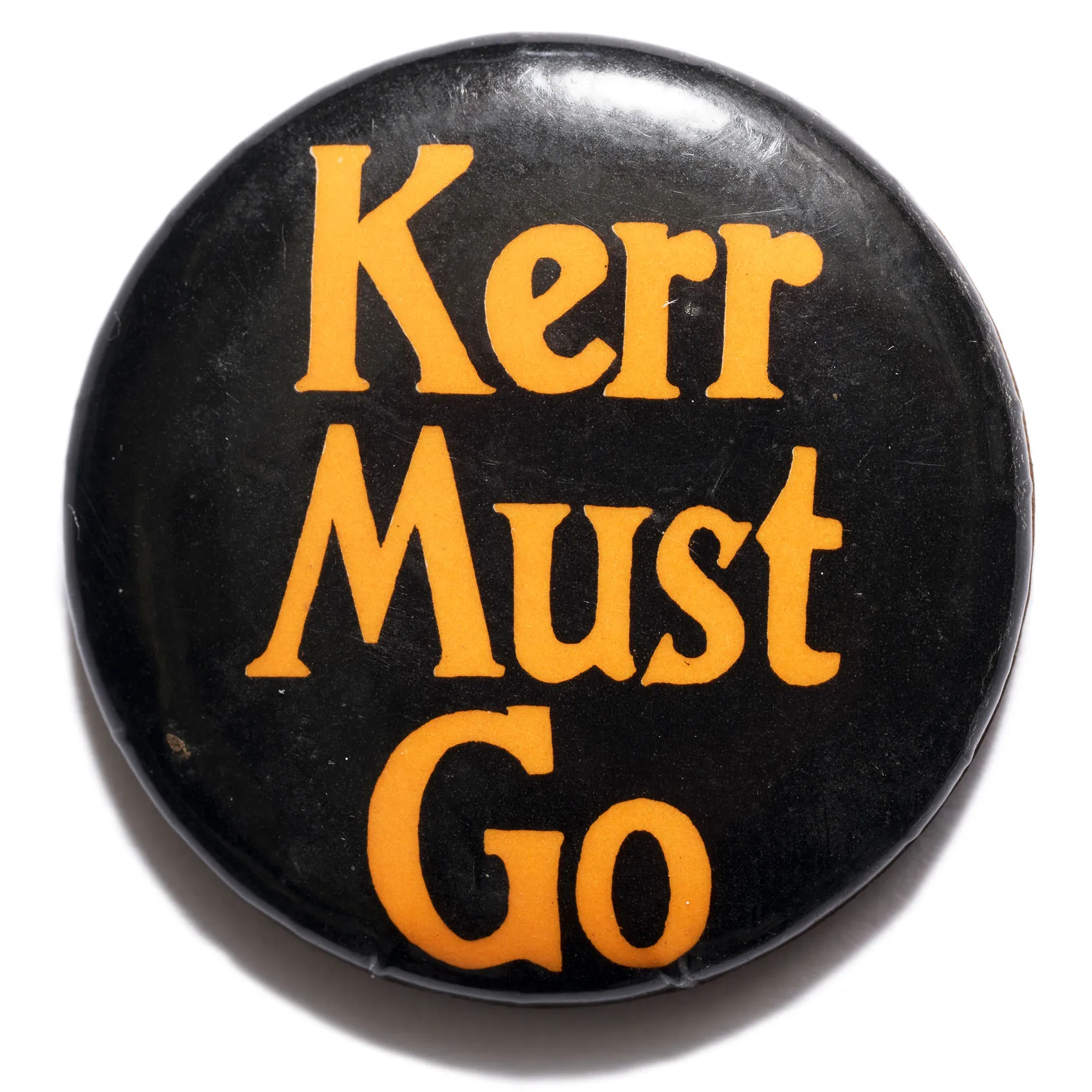 A black badge with orange text which says 'Kerr must go'.