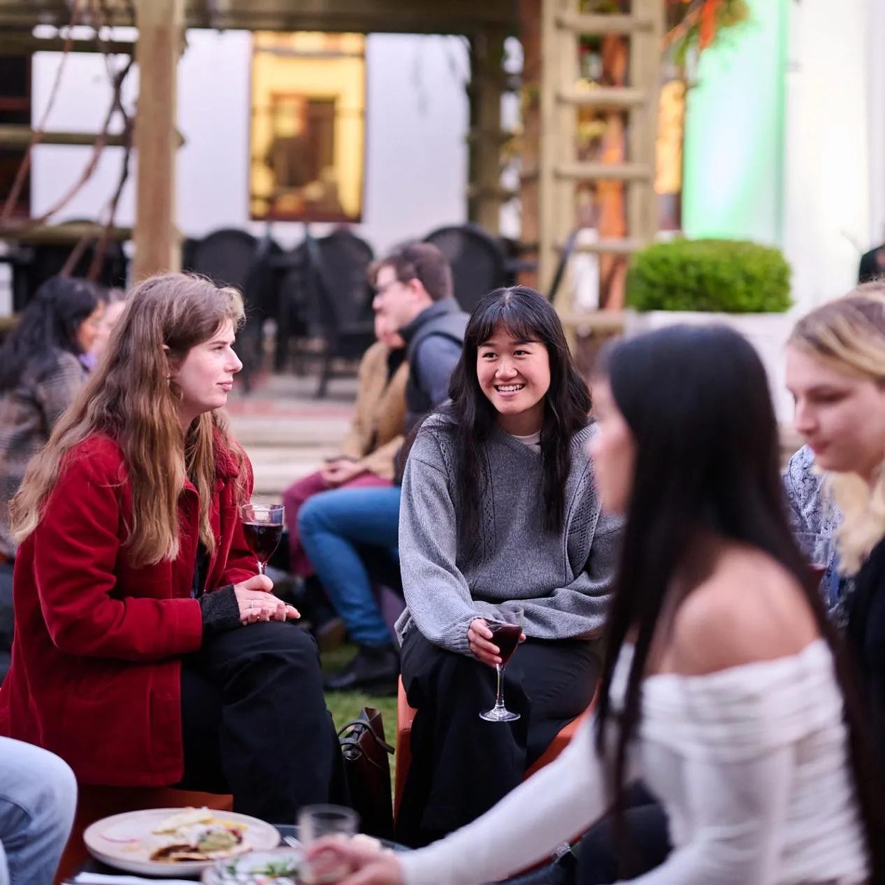 People holding wine glasses sit in the House of Representatives Courtyard in Old Parliament House.