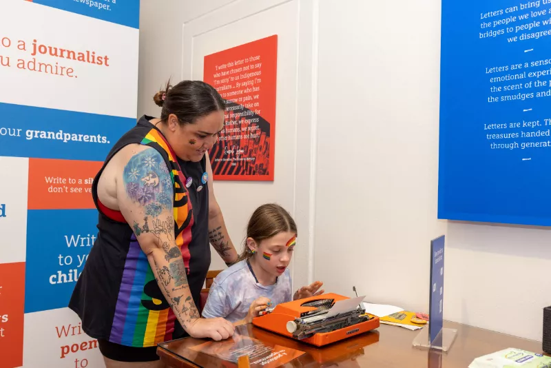 A child trying a typewriter while an adult watches on